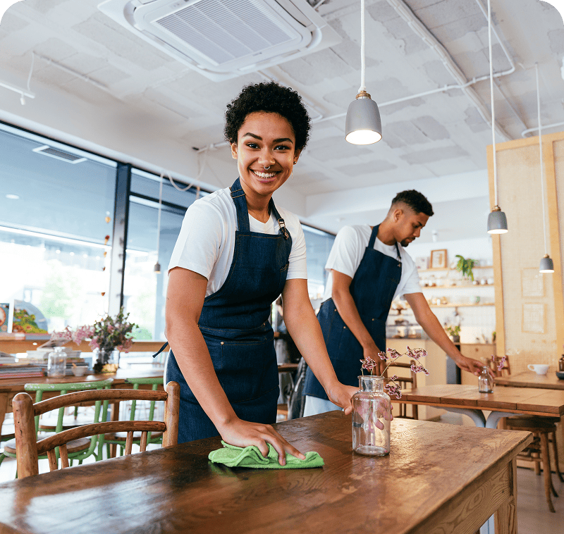 Smiling worker tidying up restaurant