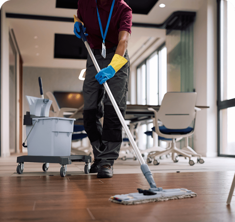 Person mopping office floor with cleaning cart.