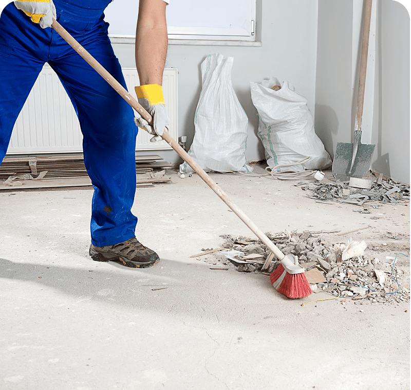 Worker sweeping construction debris with broom