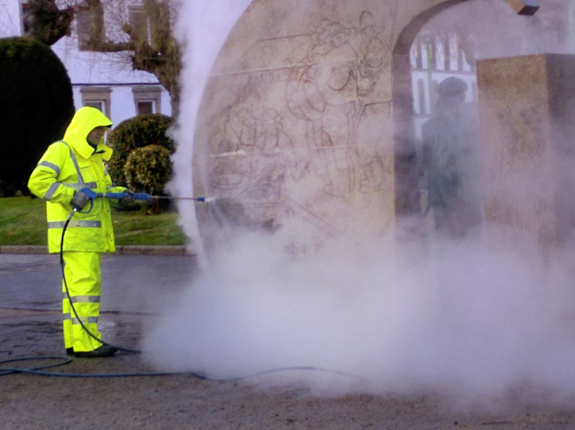 Worker cleaning an old stone wall with a pressure washer, safety equipment. Lugo city, Galicia, Spain.
