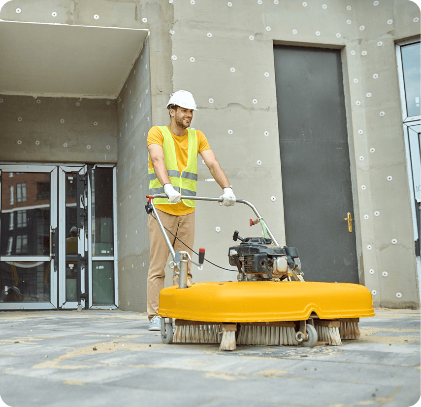 Man cleaning pavement with power sweeper