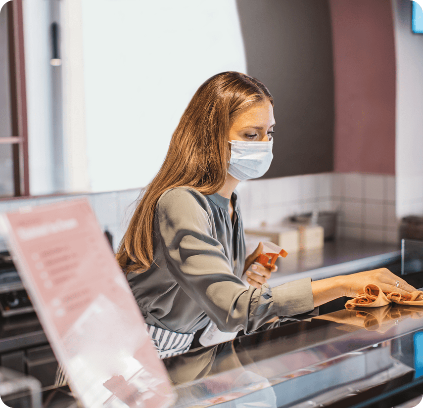 Woman cleaning counter with disinfectant spray