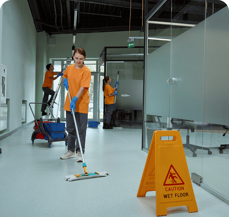 Workers cleaning office with caution sign